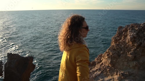 Adventure Contemplation Seascape Woman in Yellow Jacket Standing on Rocky Cliff Vertical video