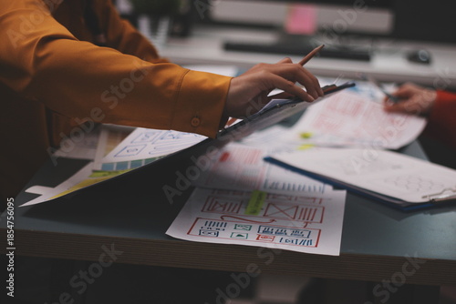 Team of uxui designers pointing at computer screen, discussing new mobile app design in the office