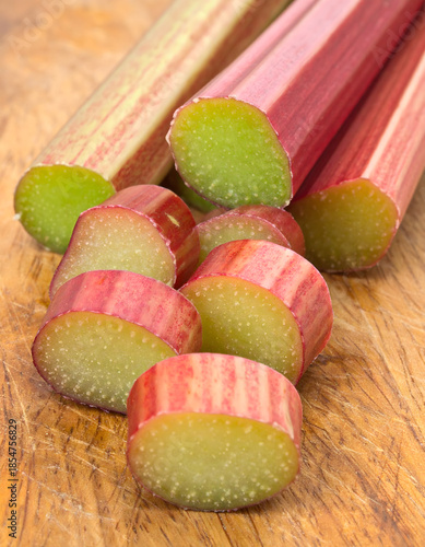Fresh Rhubarb Stalks Sliced into Rounds on Wooden Cutting Board
