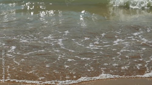 ripresa al rallentatore di piccole onde di marea che si distendono lentamente sulla sabbia di una spiaggia in Italia, di giorno, in estate