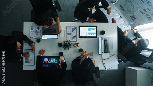 Konstfotografi Top down aerial view of smart manager pointing at financial graph on whiteboard while diverse business team explain and plan marketing idea at meeting table with stock market statistic