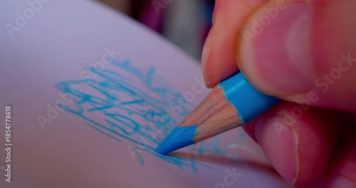 Close-up shot of hand drawing abstract pattern on paper with blue pencil