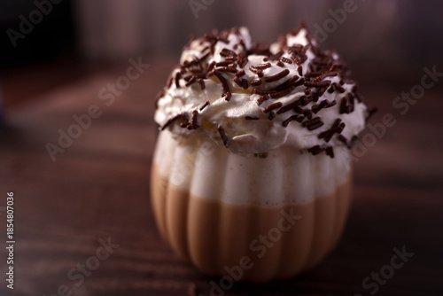 richly flavored coffee beverage in ridged glass topped with whipped cream and chocolate sprinkles on a wooden surface evoking a cozy and indulgent ambiance, dessert, savory, culinary, lush, filled