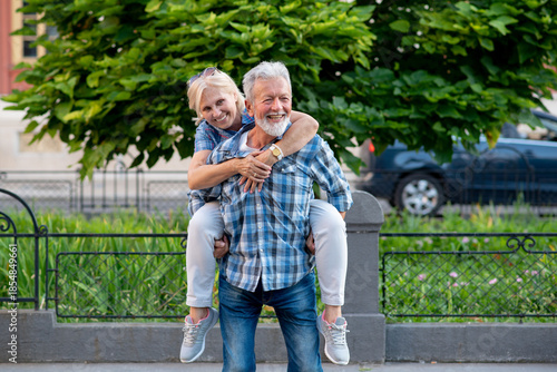 Happy senior couple having fun and enjoying outdoor piggyback ride