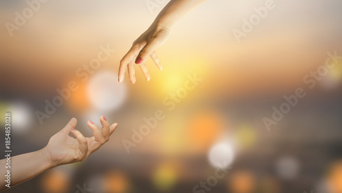 Quadro em tela Two hands are reaching out to each other against a blurred golden sunset backdrop