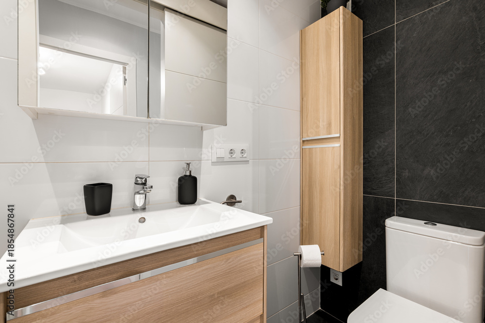 custom made wallpaper toronto digitalModern bathroom with a sleek design. Features a white sink, wooden cabinetry, a mirror, and a toilet. The walls are tiled in black and white.