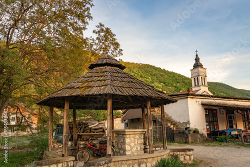 Rustic wooden pavilion sits in front of a white building with a cross on top
