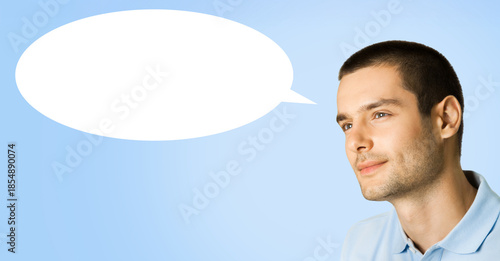 Portrait - happy smiling, looking forward, thinking, thoughtful brunette man wear polo t-shirt, isolated blue color background with empty free space mockup speech bubble. Wide banner. Ad concept image