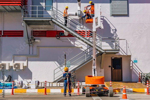 Workers are working on the Orange articulate boom lift or telescopic boom lifts and bucket crane mounted on truck for working at heights and articulating boom lift