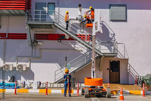 Slika na platnu Workers are working on the Orange articulate boom lift or telescopic boom lifts