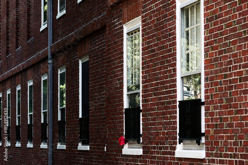 Urban Architecture: Brick Building With Tall Windows, Curtains, and Fire Alarm On Downtown Street