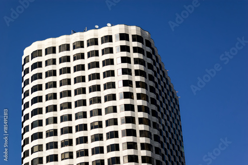 Modern Architecture: Towering Office Building with Curved Design and Blue Sky Vertical Lines