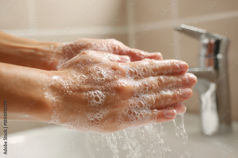 Fototapeta premium Hygiene moment: lathering soap on hands at a sink with foamy bubbles