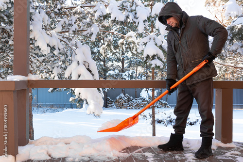 Worker man removes snow near house outdoor
