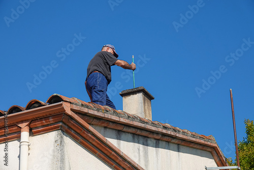 Wallpaper Mural A person works on a chimney atop a house Torontodigital.ca