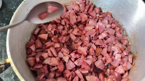 A pan on the stove frying Calabrese sausage in oil.