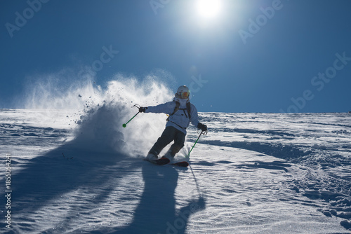Schilderij op canvas Skier skiing off piste through fresh powder on a sunny mountain slope, kicking u