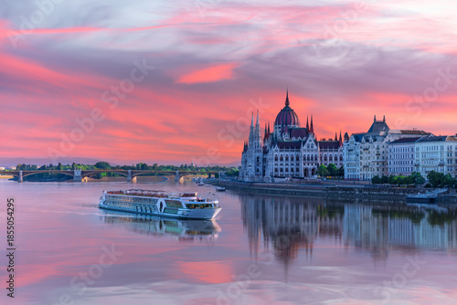 View of Budapest Parliament under sunset sky and cruise ship on the Danube, Hungary