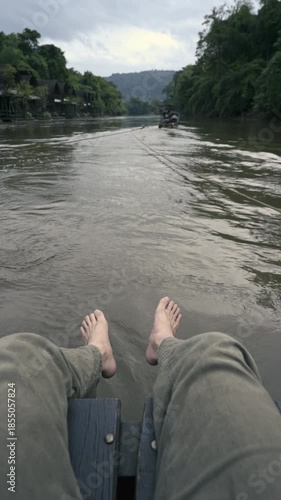 Bare feet relaxing on raft during floating on river in tropical jungle