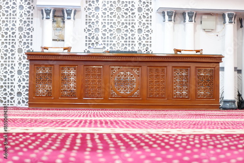 Intricately carved wooden panel in a serene prayer room with red carpet