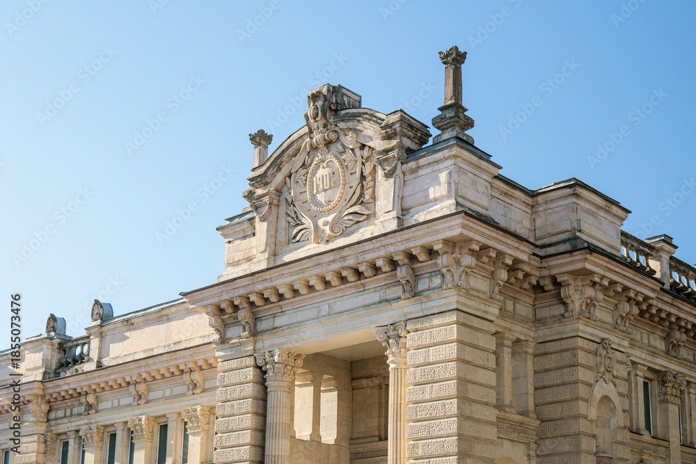Fototapeta premium Historic stone building with classical architecture and decorative facade, shot from a low angle on a sunny day in Kutaisi, Georgia. Clear blue sky creates a calm, educational and timeless atmosphere