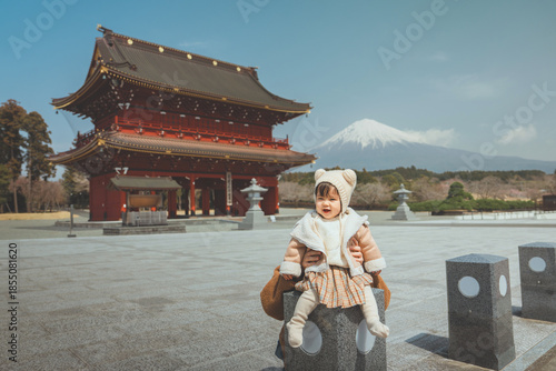 Bilde på lerret Portrait of a happy toddler girl wearing a winter bear ear hat sitting on a ston