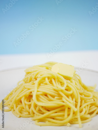 Wallpaper Mural Pile of cooked spaghetti with a butter cube on top, side view on blue and white background, simple comfort food portion of hot pasta for everyday meals Torontodigital.ca