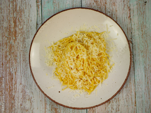 Wallpaper Mural Top view of white plate with cooked spaghetti and grated parmesan cheese on rustic wooden surface, classic Italian pasta serving for home cooking or restaurant menu Torontodigital.ca