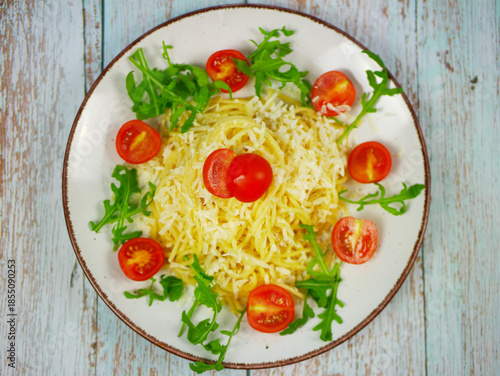 Wallpaper Mural Top view of white plate with spaghetti, grated parmesan cheese, fresh arugula and cherry tomatoes on rustic wooden background, colorful Italian pasta salad for menus and blogs Torontodigital.ca