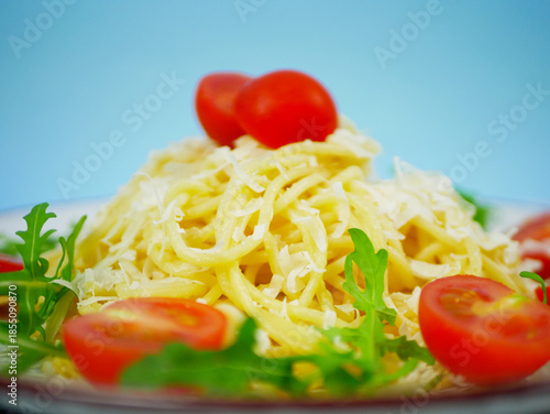 Wallpaper Mural Closeup side view of spaghetti topped with grated parmesan, cherry tomatoes and arugula on white plate against blue background, appetizing Italian pasta salad detail. Pro Photo Torontodigital.ca