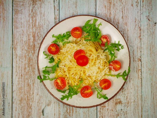 Wallpaper Mural Top view of spaghetti with grated parmesan, arugula leaves and cherry tomato halves arranged in circle on white plate over rustic wooden table, Italian pasta salad Torontodigital.ca