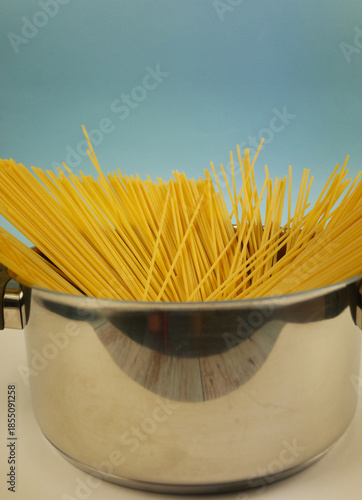 Wallpaper Mural Front view of metal pot filled with upright uncooked spaghetti pasta against blue and white background, minimal Italian cuisine concept with dry noodles and copy space Torontodigital.ca