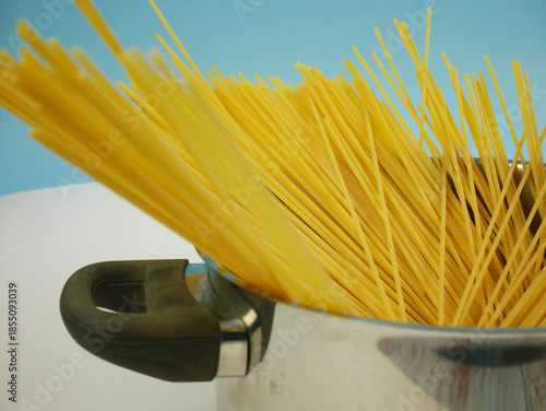 Wallpaper Mural Uncooked spaghetti pasta leaning out of a metal pot with handle on blue and white background, simple Italian food ingredient image for cooking themes and kitchen design Torontodigital.ca