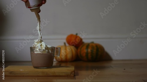 Pouring whipped cream onto hot chocolate drink