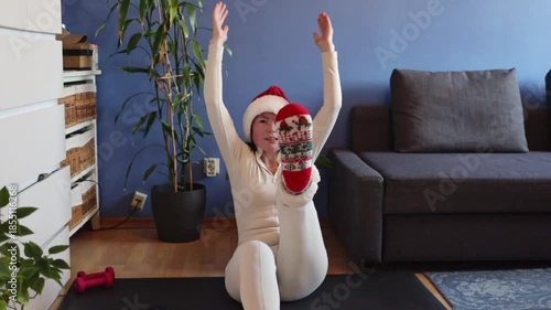 A mature, slender girl in a Santa Claus hat performs the navasana exercise.