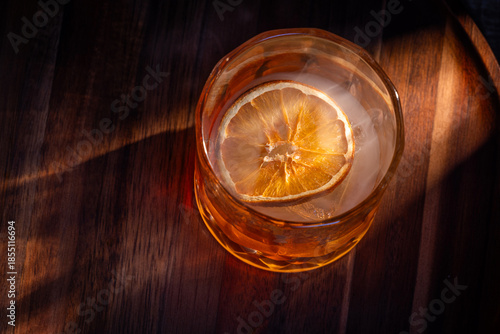 Wallpaper Mural whiskey cocktail served on the rocks garnished with a dehydrated orange slice with dramatic lighting served on a wooden surface. Torontodigital.ca