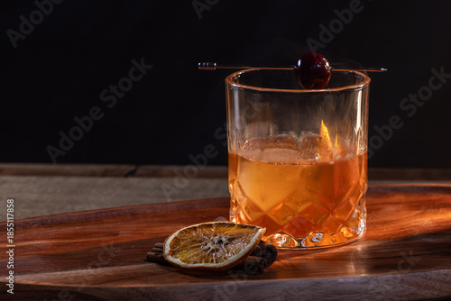 Wallpaper Mural whiskey cocktail served on the rocks garnished with a dehydrated orange slice and a cherry with dramatic lighting served on a wooden surface. Torontodigital.ca