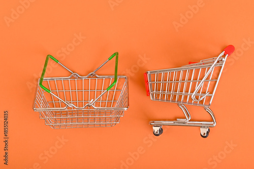 Empty shopping cart and basket on orange background
