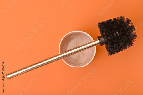 Toilet brush with metal handle on orange background