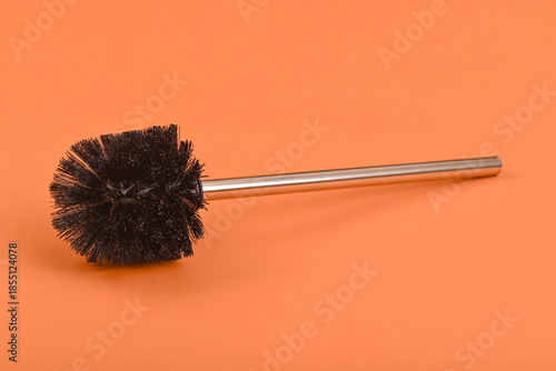 Toilet brush with metal handle on orange background