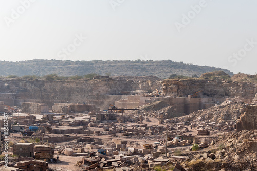 industrial mining operations in large rock quarry under bright daylight in Aravalli range
