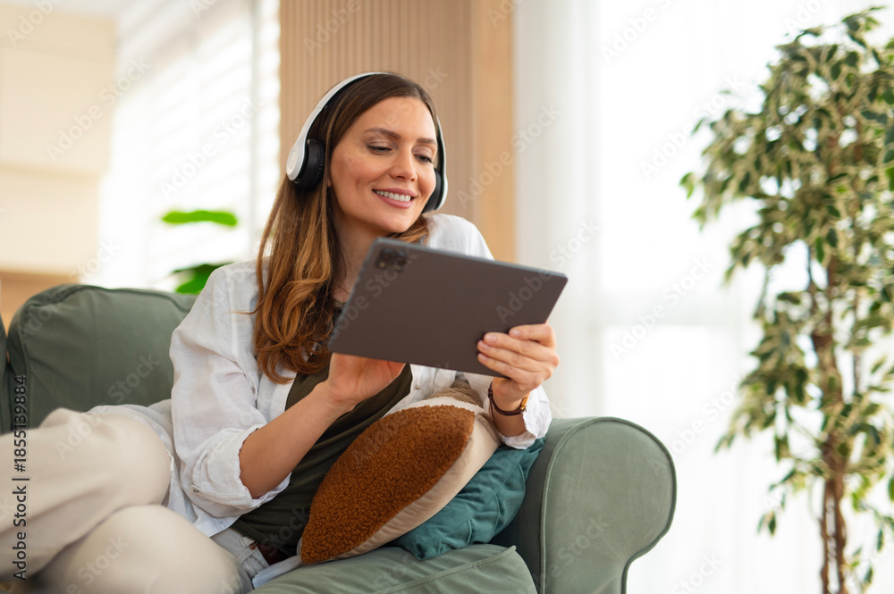 Fototapeta premium Woman relaxing at home checking social media on tablet