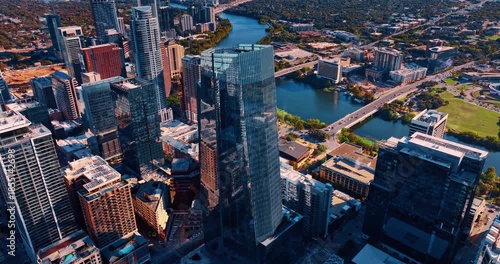 Glass skyscraper of unusual shape in the downtown of Houston, Texas, USA. Cars go by the bridges over the Colorado River crossing the city.