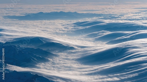 Aerial view captures dramatic, wave-like formations of snow and clouds above mountain ranges