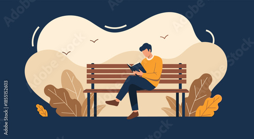 Young man sitting comfortably on a wooden park bench and reading a book against a warm autumn landscape with falling leaves.
