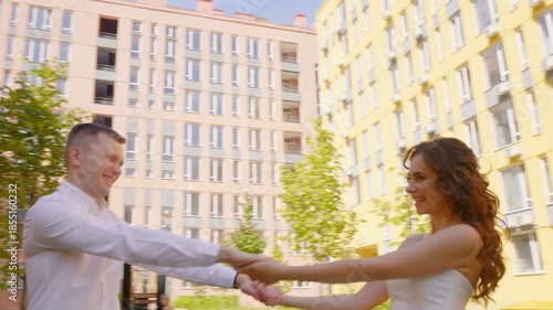 Fun Bride and groom Couple Dancing and spinning around Outdoors outside a colorful yellow building, capturing a moment of celebration, connection, and happiness in an urban outdoor scene 4K UHD