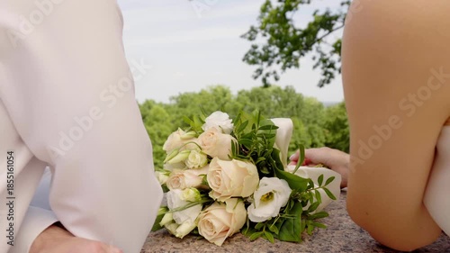 Bride And Groom Share A Tender Moment Outdoors On A Balcony in Public Park With a wedding bouquet against the background of green trees under a bright sky 4K UHD B-Roll