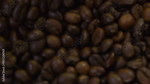 Selective focus. Falling coffee beans in slow motion. Smoke emanates from fresh coffee beans.