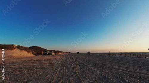 Driving on the beach in Port Aransas as the sun rises above the horizon over the water on Mustang Island, a barrier island along the Texas coast.