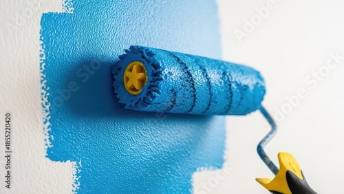 Paint roller applying vibrant blue paint to a white wall during home renovation.